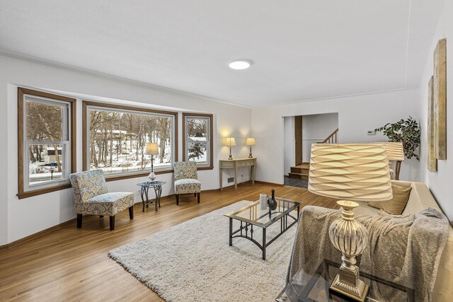 living room featuring a healthy amount of sunlight, stairs, baseboards, and wood finished floors