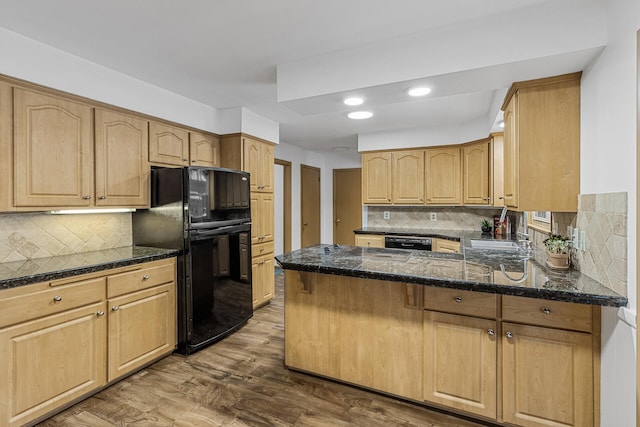 kitchen featuring a peninsula, a sink, wood finished floors, decorative backsplash, and black appliances