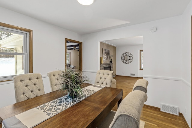 dining space with light wood-style floors, a fireplace, visible vents, and a healthy amount of sunlight