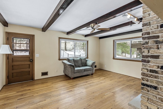 entrance foyer with visible vents, plenty of natural light, beamed ceiling, and light wood finished floors