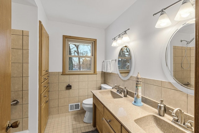 bathroom featuring visible vents, a sink, tile walls, and toilet