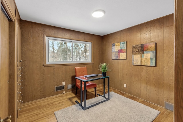 office with visible vents, wood walls, and light wood-style flooring