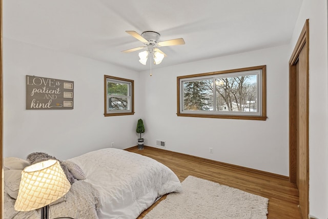 bedroom with a closet, multiple windows, visible vents, and wood finished floors