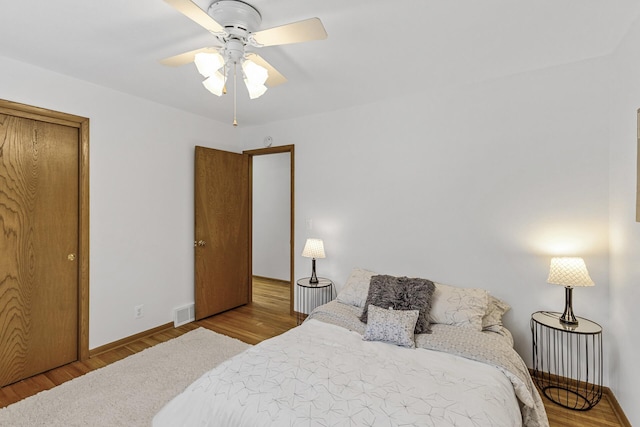 bedroom featuring baseboards, wood finished floors, visible vents, and a ceiling fan