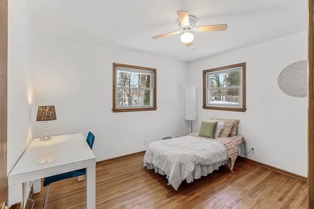 bedroom featuring multiple windows, baseboards, and wood finished floors