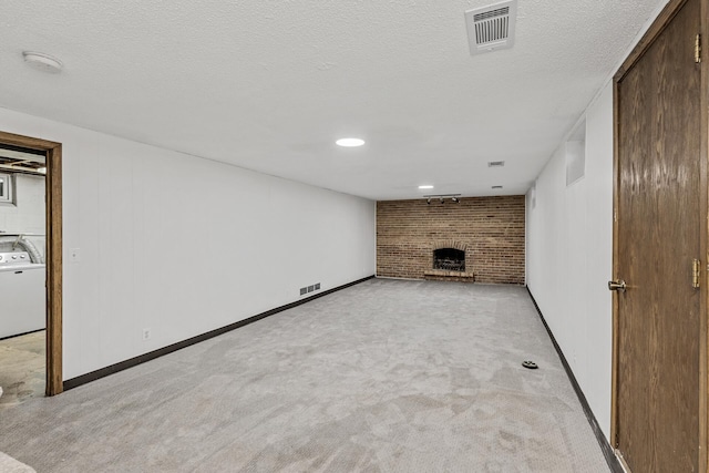 finished basement with light carpet, washer / dryer, a fireplace, and visible vents