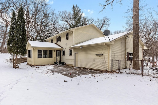 snow covered back of property with entry steps and fence