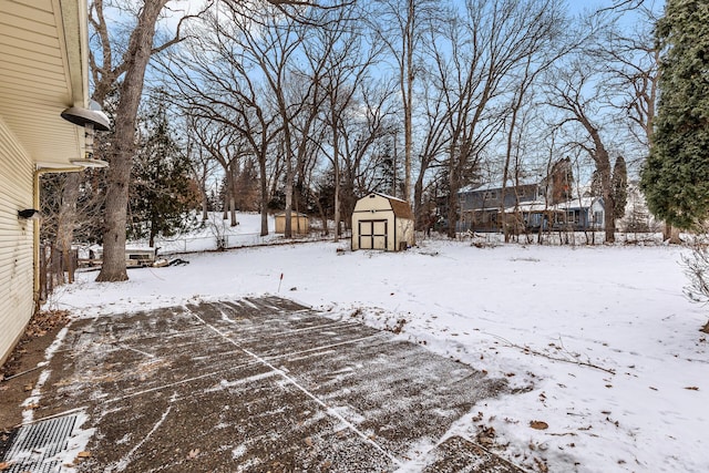 yard layered in snow with a storage shed, fence, and an outbuilding