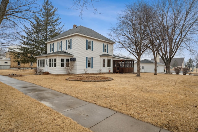 view of front of house featuring a shingled roof, a chimney, and a front yard