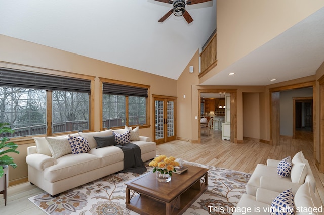 living area featuring high vaulted ceiling, light wood-style flooring, a ceiling fan, baseboards, and french doors