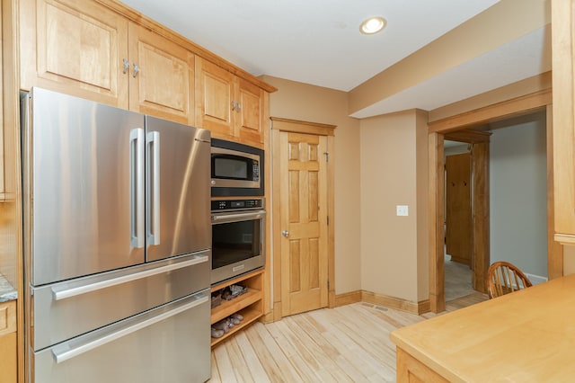 kitchen with baseboards, appliances with stainless steel finishes, light countertops, light wood-style floors, and light brown cabinets