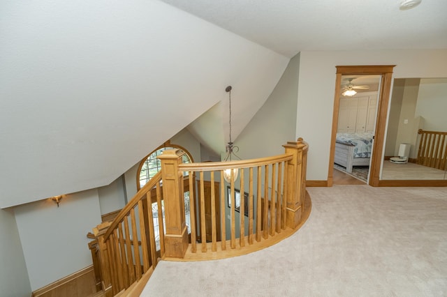 hall with carpet floors, lofted ceiling, an upstairs landing, a chandelier, and baseboards