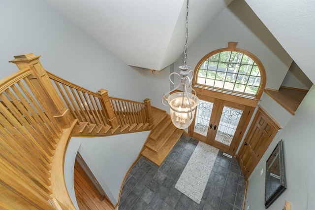 foyer entrance with french doors, an inviting chandelier, a textured ceiling, high vaulted ceiling, and stairs