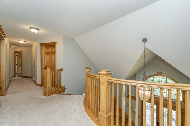 corridor with vaulted ceiling, carpet floors, an upstairs landing, and baseboards