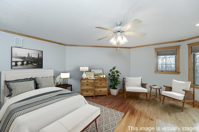 bedroom featuring a ceiling fan, light wood-type flooring, crown molding, and baseboards