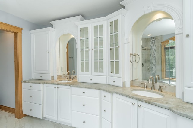 bathroom with marble finish floor, double vanity, a sink, and a shower stall