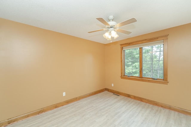 unfurnished room with visible vents, a ceiling fan, light wood-style flooring, and baseboards