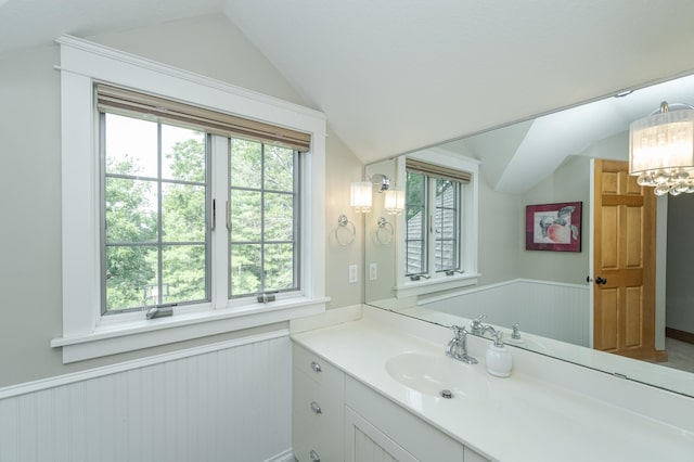 bathroom featuring lofted ceiling, wainscoting, and a wealth of natural light