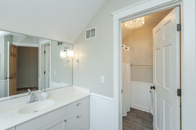 full bathroom featuring visible vents, wainscoting, wood tiled floor, vaulted ceiling, and vanity