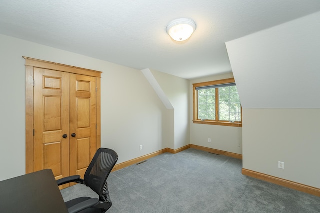 carpeted office space featuring vaulted ceiling and baseboards