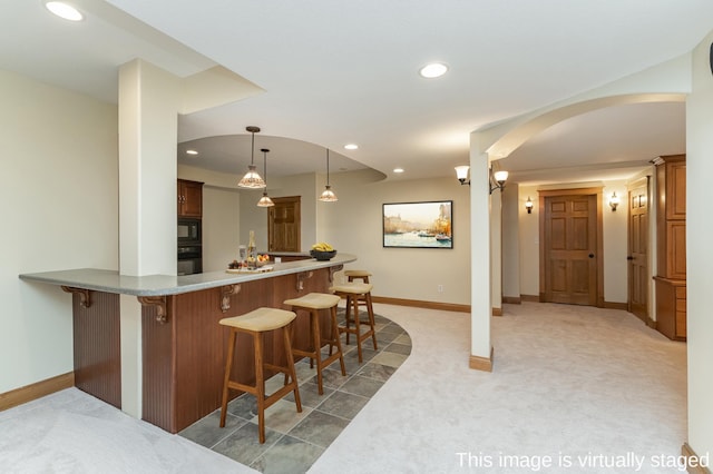 kitchen with a kitchen breakfast bar, black appliances, and light colored carpet