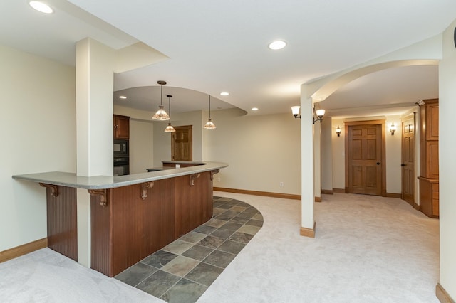 kitchen featuring a breakfast bar, dark carpet, a peninsula, and black appliances