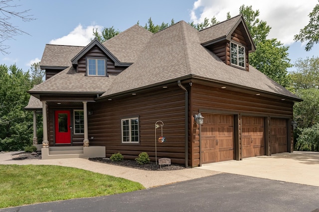 cabin with a garage, a shingled roof, and concrete driveway