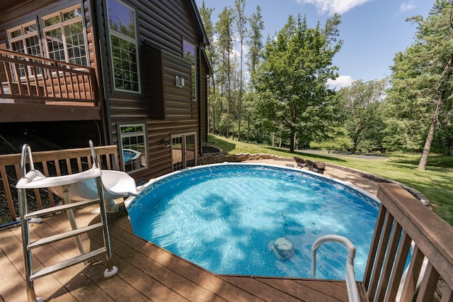 view of swimming pool featuring a lawn, a wooden deck, and a jacuzzi