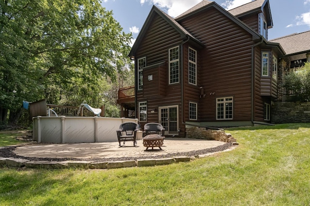 rear view of property featuring a patio area, faux log siding, and a lawn