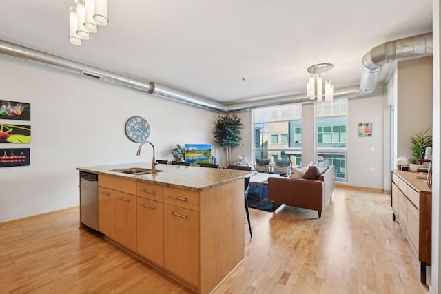 kitchen featuring a center island with sink, hanging light fixtures, open floor plan, a sink, and dishwasher