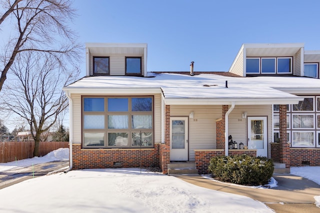 view of front of home featuring crawl space, brick siding, fence, and covered porch