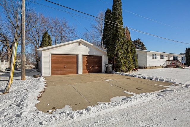 snow covered garage featuring a detached garage