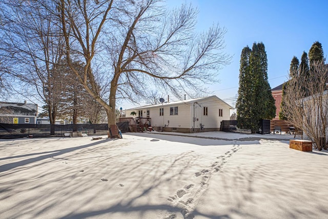 snow covered rear of property featuring fence