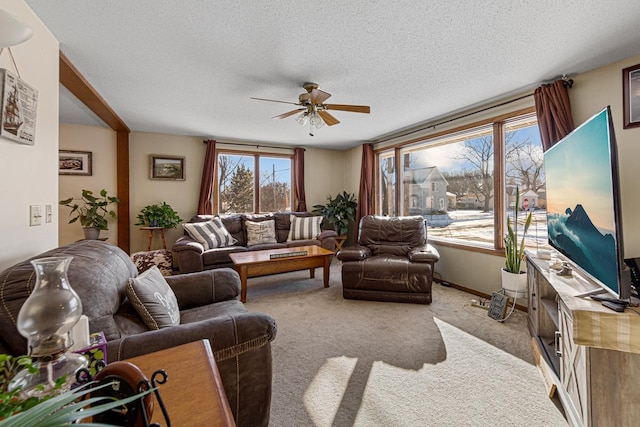 living area with baseboards, a ceiling fan, a textured ceiling, and light colored carpet