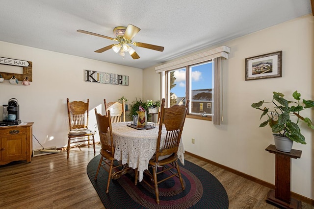 dining area with ceiling fan, baseboards, dark wood finished floors, and a textured ceiling