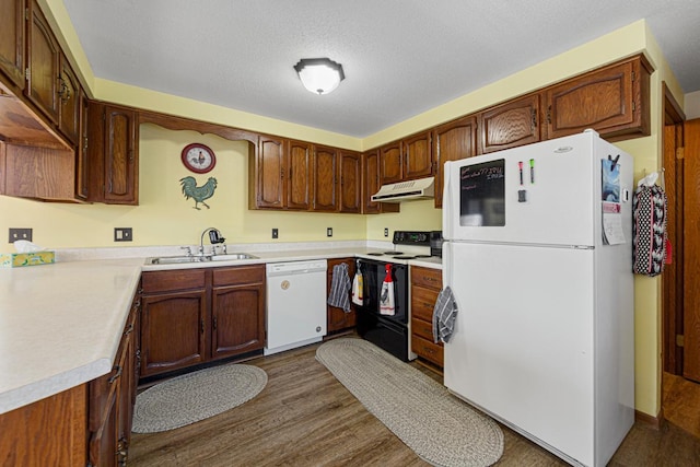 kitchen with dark wood-style floors, light countertops, a sink, white appliances, and under cabinet range hood