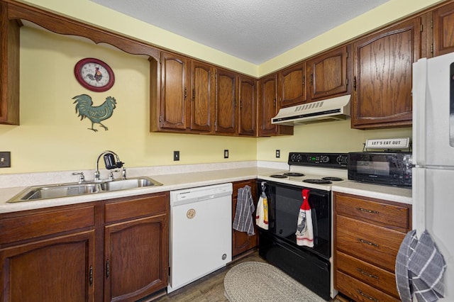 kitchen featuring white appliances, light countertops, a sink, and under cabinet range hood