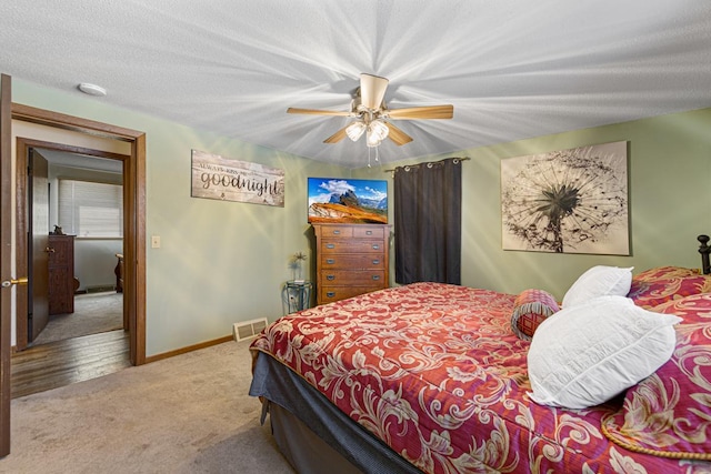 bedroom featuring carpet floors, visible vents, ceiling fan, a textured ceiling, and baseboards