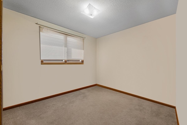 spare room featuring a textured ceiling, baseboards, and carpet flooring