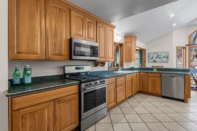 kitchen featuring light tile patterned floors, a sink, vaulted ceiling, appliances with stainless steel finishes, and dark countertops