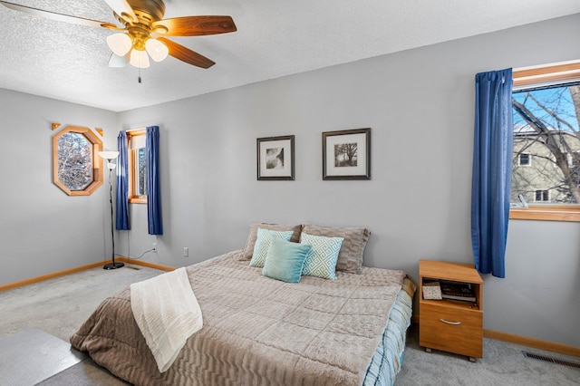 bedroom featuring light carpet, a textured ceiling, visible vents, and baseboards