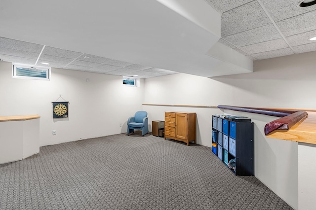 basement featuring a paneled ceiling and carpet flooring