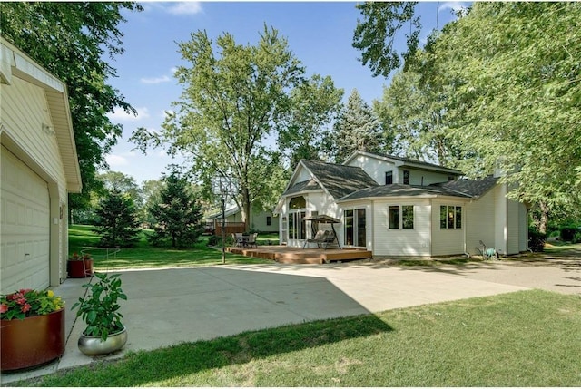 view of yard with a deck, concrete driveway, and a patio