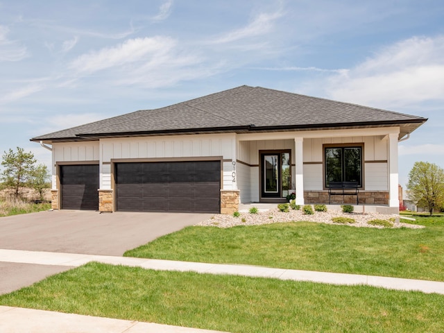 prairie-style home with driveway, stone siding, roof with shingles, an attached garage, and board and batten siding