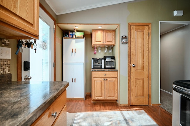 kitchen featuring dark countertops, vaulted ceiling, light wood-style flooring, and stainless steel electric range