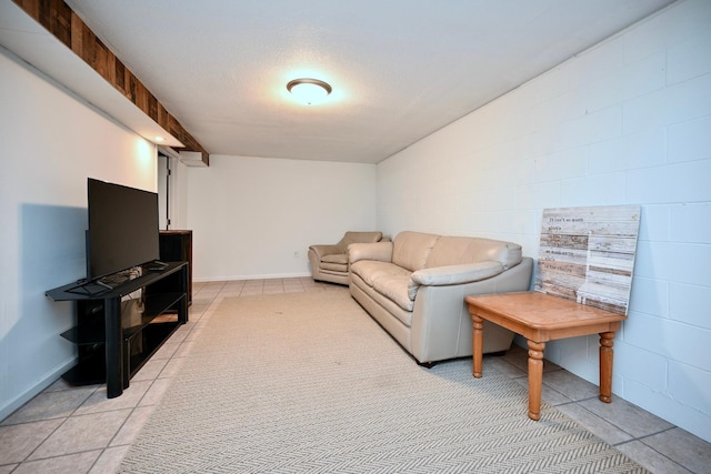 living room with light tile patterned floors, a textured ceiling, concrete block wall, and baseboards