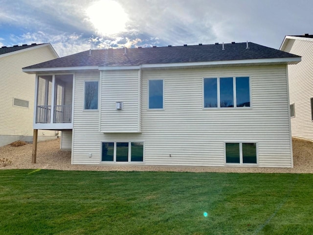 back of house featuring a shingled roof and a lawn