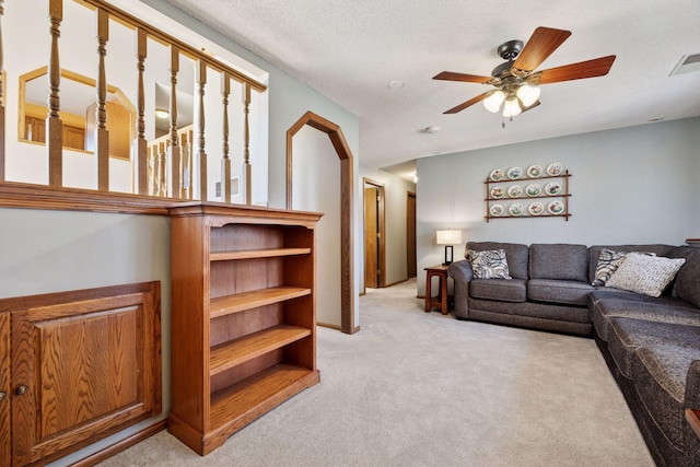 living room with light carpet, visible vents, a textured ceiling, and a ceiling fan