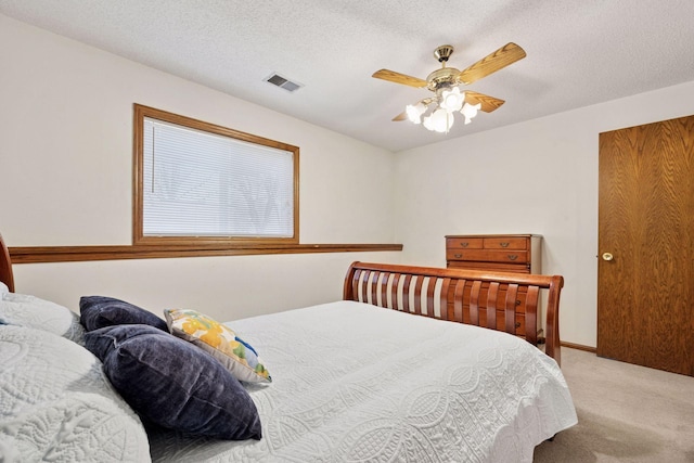 carpeted bedroom with a textured ceiling, ceiling fan, and visible vents