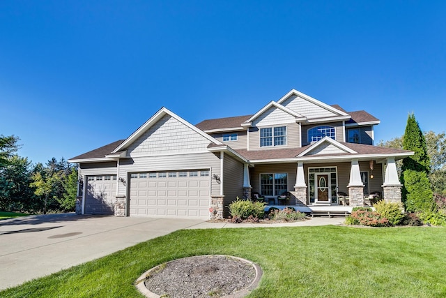 craftsman-style house featuring covered porch, a garage, stone siding, concrete driveway, and a front lawn